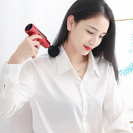 Woman using red PulseMini massage gun for neck and shoulder tension relief at home or office - quiet operation with digital display